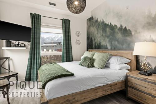 a bedroom with a bed with a painting on the wall at Mountain Haven Retreat, Pool & Hot Tub, UG Parking, Fitness Centre, WiFi! in Canmore