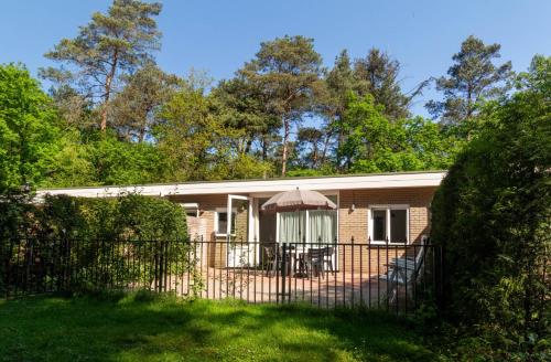 a house with an umbrella and a fence at Hoefbos bungalow in Otterlo