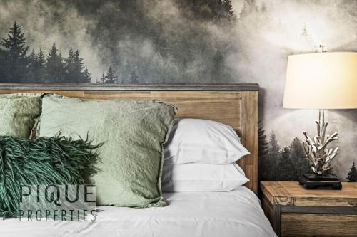 a bedroom with a bed with a painting on the wall at Mountain Haven Retreat, Pool & Hot Tub, UG Parking, Fitness Centre, WiFi! in Canmore