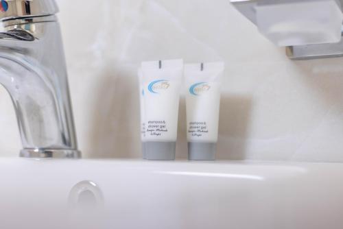 dois tubos de pasta de dentes sentados num lavatório da casa de banho em Hotel Vila MAX em Durrës
