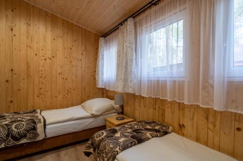 two beds in a room with a window at Domki Zacisze, Okoniny in Śliwice