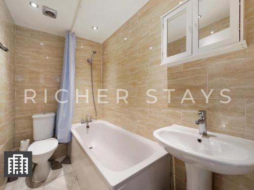 La salle de bains est pourvue d'un lavabo, de toilettes et d'une baignoire. dans l'établissement Hackney Guest Rooms, à Londres