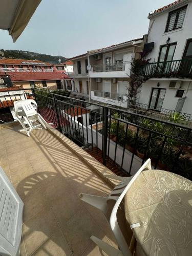 a balcony with two white chairs and a building at Pansion Angela in Skiathos Town