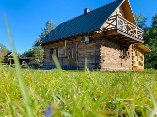 a wooden cabin with a metal roof in a field of grass at Sielankowe Pole in Józefów
