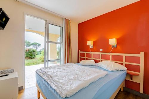 une chambre avec un lit avec un mur orange dans l'établissement Résidence le Village de Cap Esterel - maeva Home - Appartement vue mer 2 pièces 5 personnes - Prestige MAE-2374, à Saint-Raphaël