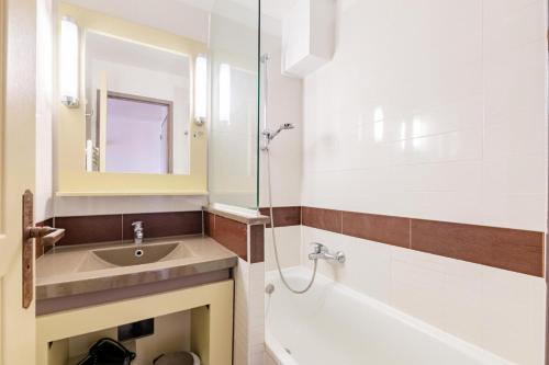 une salle de bain avec un lavabo, une baignoire et un miroir dans l'établissement Résidence le Village de Cap Esterel - maeva Home - Appartement vue mer 2 pièces 5 personnes - Prestige MAE-2374, à Saint-Raphaël
