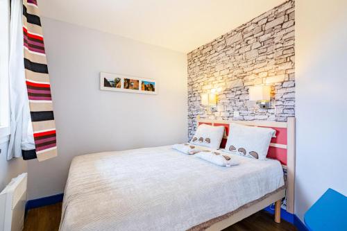 - une chambre avec un lit blanc et un mur en briques dans l'établissement Résidence le Village de Cap Esterel - maeva Home - Appartement 2 pièces 4 personnes - Sélection MAE-7584, à Saint-Raphaël