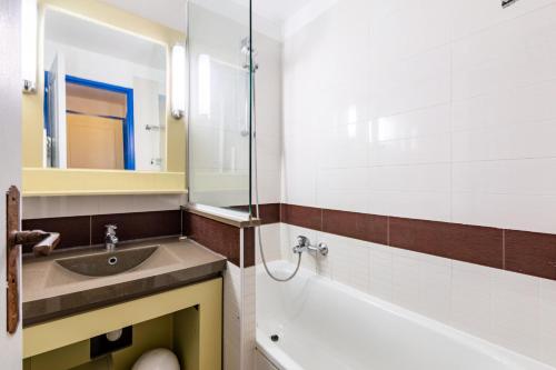 une salle de bain avec un lavabo, une baignoire et un miroir dans l'établissement Résidence le Village de Cap Esterel - maeva Home - Appartement 2 pièces 4 personnes - Sélection MAE-7584, à Saint-Raphaël
