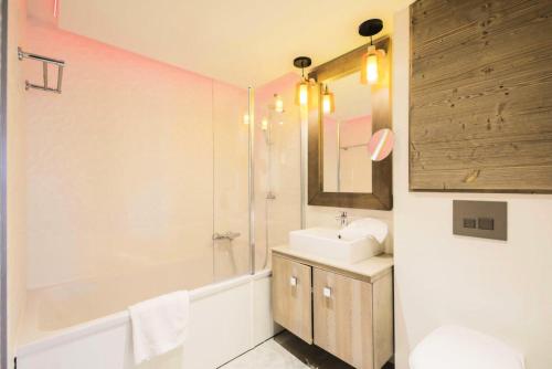 Les AlluesにあるRésidence Premium L'Hévana - maeva Home - Appartement 2 pièces 4 personne 054のバスルーム(シンク、鏡、バスタブ付)