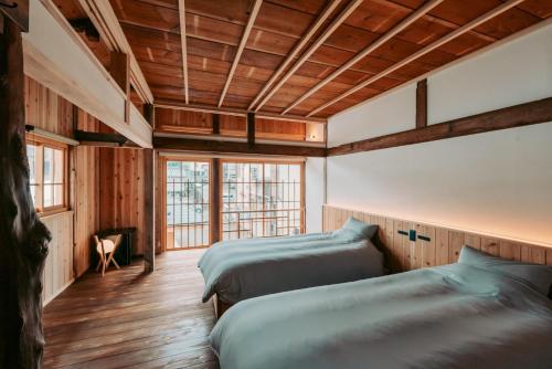 two beds in a room with wooden walls and wooden floors at Ikeda Ryokan - Vacation STAY 79302v in Nishinoomote