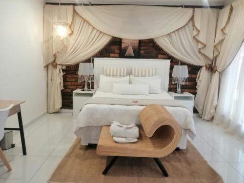 a bedroom with a large white bed and a table at Ledimor Guesthouse in Polokwane