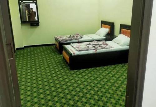 2 camas en una habitación con alfombra verde en Swat Inn Hotel en Mingora