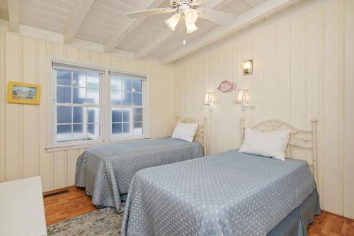 a bedroom with two beds and a ceiling fan at Smart Pelican by Oak Island Accommodations in Oak Island