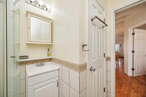 a white bathroom with a sink and a mirror at Smart Pelican by Oak Island Accommodations in Oak Island