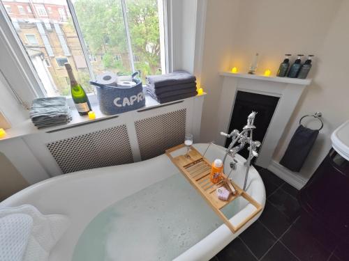 STUNNING 4 BEDROOM FLAT IN REGENT'S PARK - ABBEY Rd في لندن: حمام مع حوض استحمام ومدفأة