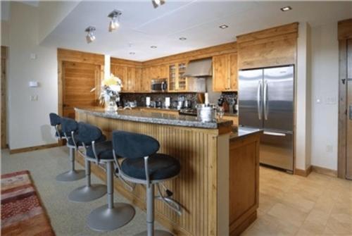 a kitchen with wooden cabinets and a bar with bar stools at The Lodge at Mountaineer Square in Mount Crested Butte