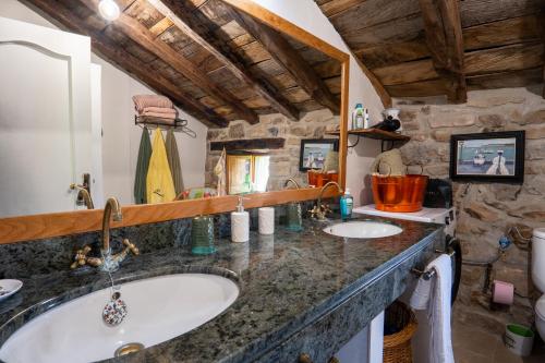 baño con 2 lavabos y pared de piedra en Cabaña pasiega LO LUCAS 1920, en San Roque de Ríomiera