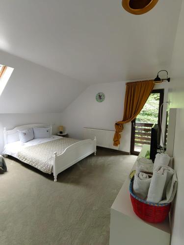 a white bedroom with a bed and a window at Casuta Din Padure Malaia in Malaia