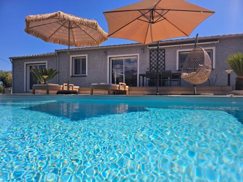 una piscina con 2 sombrillas y una casa en Chambre d'hôtes Corse Villa Moorea chez l'habitant, en Ventiseri