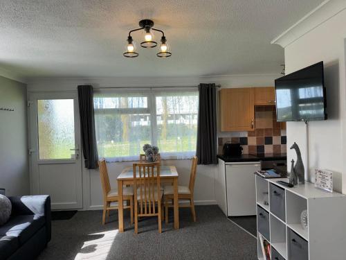 a living room with a table and a kitchen at 62 M&T Chalets , 2 bed detached chalet Florida holiday park Hemsby in Hemsby
