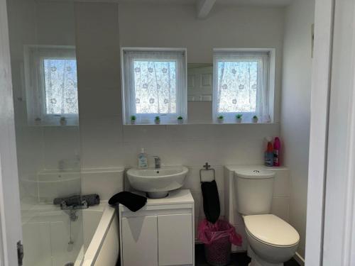 a white bathroom with a toilet and a sink at 62 M&T Chalets , 2 bed detached chalet Florida holiday park Hemsby in Hemsby