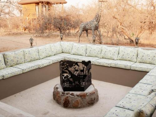 a couch with a giraffe standing in the background at Maroelani Lodge- Greater Kruger Private Reserve in Hoedspruit