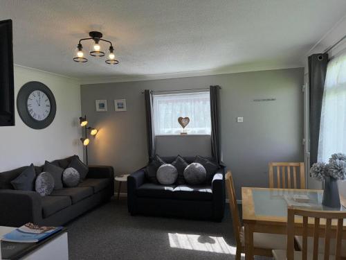 a living room with a couch and a window at 62 M&T Chalets , 2 bed detached chalet Florida holiday park Hemsby in Hemsby