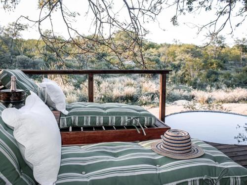 two beds on a porch with a table with hats at Maroelani Lodge- Greater Kruger Private Reserve in Hoedspruit