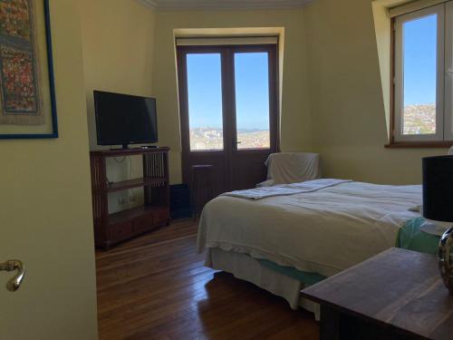 a bedroom with a bed and a flat screen tv at En el corazon del Cerro Alegre in Valparaíso