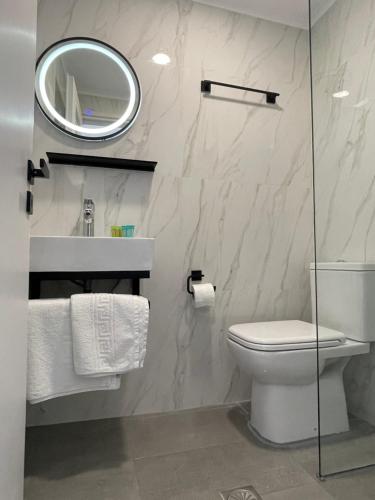 W łazience znajduje się toaleta, umywalka i lustro. w obiekcie Sunshine Apartments and Rooms w mieście Nikiana