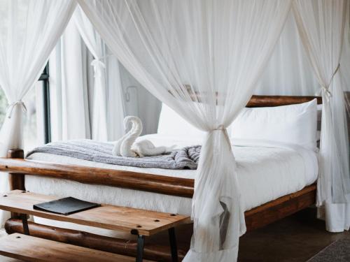 侯斯普瑞特的住宿－Maroelani Lodge- Greater Kruger Private Reserve，一间卧室配有一张天蓬床和天鹅