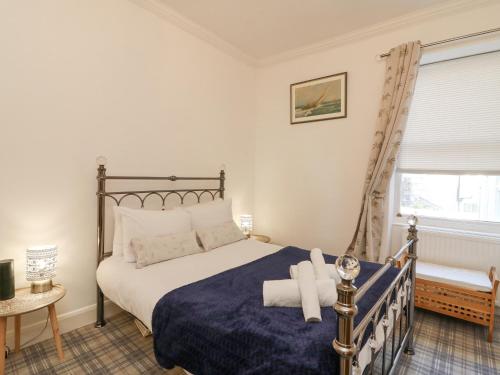 een slaapkamer met een bed met een blauwe deken en een raam bij The Aquamarine Sea View Apartment in Weymouth