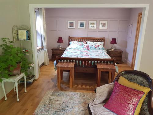 ein Schlafzimmer mit einem Bett mit zwei Tischen und einem Sofa in der Unterkunft Pink Granite Garden of Ireland in Tinahely
