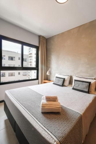 a bedroom with a large bed with a large window at Club Haas Higienópolis in São Paulo
