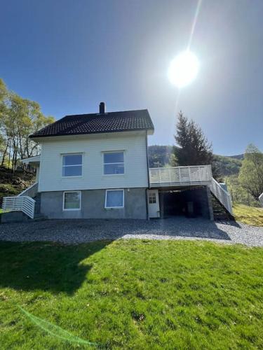 a large white house with a balcony and a yard at Feriehus og naust i idylliske omstendigheter in Tjørvåg
