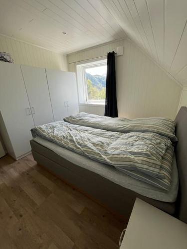 a bed in a room with a window at Feriehus og naust i idylliske omstendigheter in Tjørvåg