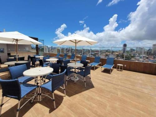 a rooftop patio with tables and chairs and umbrellas at Studio, lindo, novo, praia! in Salvador