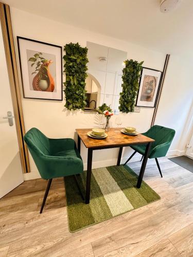 a dining room with a table and two green chairs at Newly Renovated En-Suite Private Room in Birmingham Selly Oak R1 in Birmingham