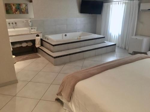 a bathroom with a tub and a sink and a bed at Hotel Fazenda Santa Monica in Louveira