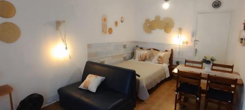 大普拉亚Kitnet Temporada Praia Grande SP - Completa com Wi-fi, garagem rotativa, 1 quadra da praia - no centro comercial Boqueirão的带床和椅子的卧室