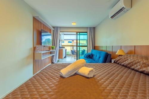 a bedroom with a bed and a blue chair at Tangaroa Flats em Porto de Galinhas por Carpediem in Porto De Galinhas