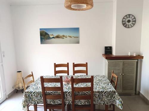 une salle à manger avec une table, des chaises et une horloge dans l'établissement Oasis au Chenal - Proche Plage, à Grand-Fort-Philippe