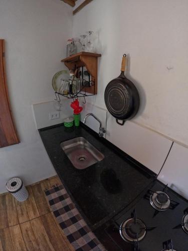 a kitchen with a sink and a pot on the wall at Chalés Vila Carrancas - Ao lado do centro com piscina, cozinha completa e muita tranquilidade in Carrancas