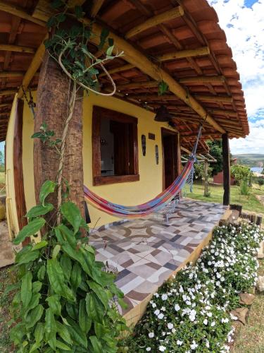 a porch of a house with a hammock on it at Chalés Vila Carrancas - Ao lado do centro com piscina, cozinha completa e muita tranquilidade in Carrancas