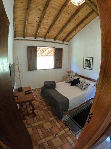 a bedroom with a bed and a table and a window at Chalés Vila Carrancas - Ao lado do centro com piscina, cozinha completa e muita tranquilidade in Carrancas