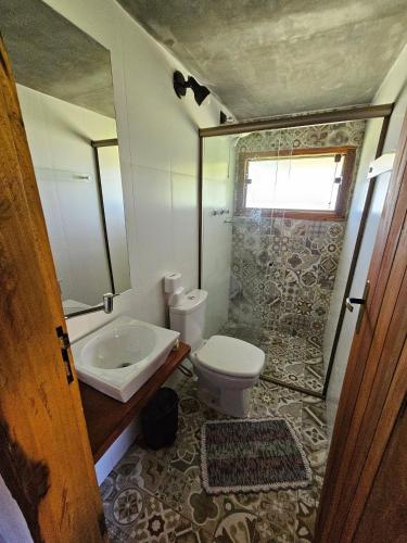 a bathroom with a sink and a toilet and a shower at Chalés Vila Carrancas - Ao lado do centro com piscina, cozinha completa e muita tranquilidade in Carrancas
