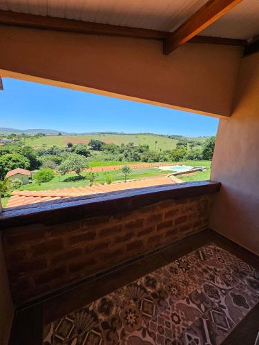 a room with a window with a view of a field at Chalés Vila Carrancas - Ao lado do centro com piscina, cozinha completa e muita tranquilidade in Carrancas
