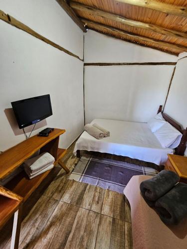 a bedroom with a bed and a tv in a room at Chalés Vila Carrancas - Ao lado do centro com piscina, cozinha completa e muita tranquilidade in Carrancas