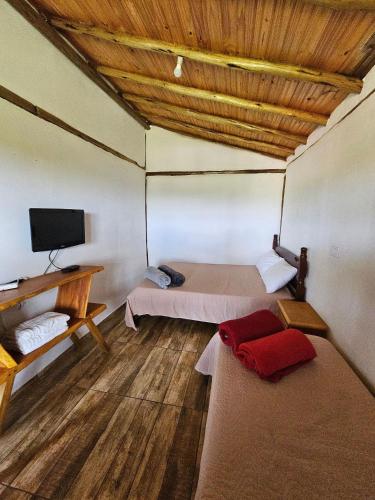 a room with two beds and a flat screen tv at Chalés Vila Carrancas - Ao lado do centro com piscina, cozinha completa e muita tranquilidade in Carrancas