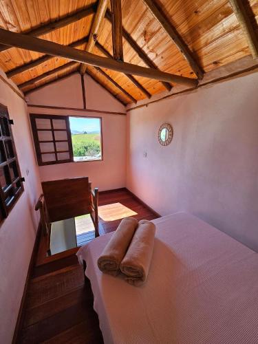 a bedroom with a bed with two towels on it at Chalés Vila Carrancas - Ao lado do centro com piscina, cozinha completa e muita tranquilidade in Carrancas